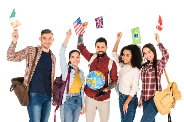 Homem bonito segurando globo e de pé com grupo multiétnico de pessoas segurando bandeiras de diferentes países acima cabeças isoladas em branco — Fotografia de Stock