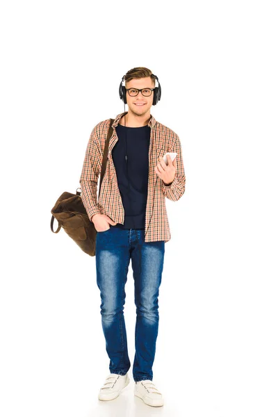 Handsome man standing in headphones and holding  smartphone isolated on white — Stock Photo