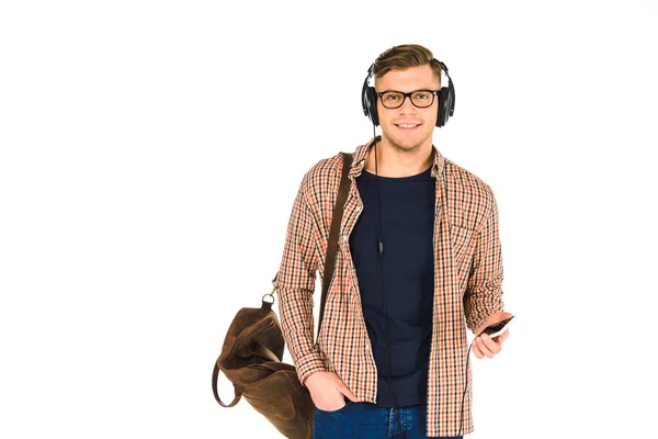 Красивий чоловік слухає музику в навушниках і тримає смартфон ізольовано на білому — стокове фото