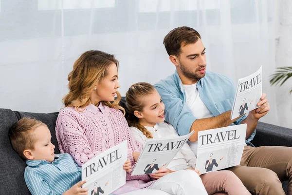 Felice famiglia seduta sul divano e leggere giornali di viaggio in appartamento — Foto stock