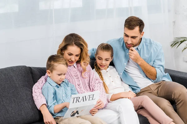 Famiglia seduta sul divano e lettura giornale di viaggio in soggiorno — Foto stock