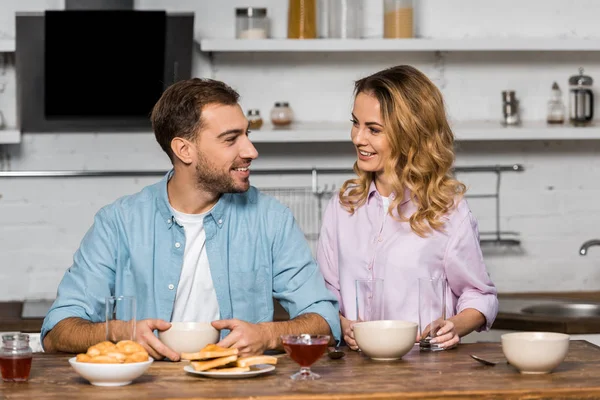 Улыбающаяся семейная пара смотрит друг на друга на кухне — стоковое фото