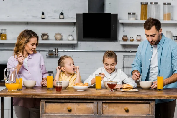 Familia feliz comer gachas para el desayuno en la cocina - foto de stock