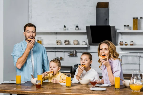 Família feliz comer torradas com geléia à mesa na cozinha — Fotografia de Stock