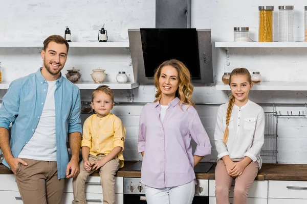 Усміхнені батьки з дочкою і сином дивляться на камеру на кухні — стокове фото