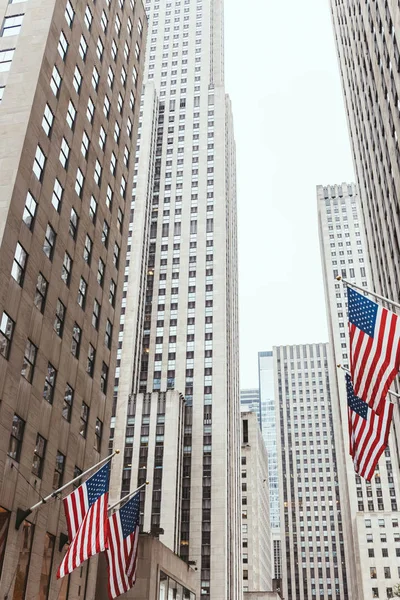 Baixo ângulo de visão de arranha-céus e bandeiras americanas na rua da cidade de Nova Iorque, EUA — Fotografia de Stock