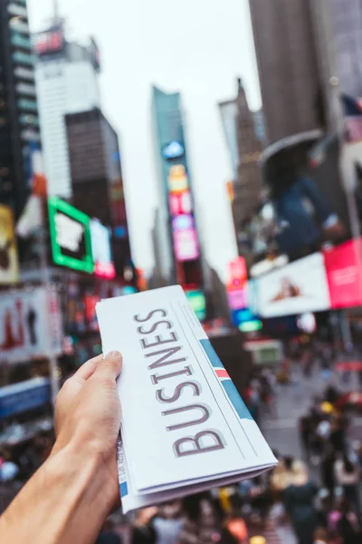 Partial view of man holding business newspaper with blurry new york street city view on background — Stock Photo