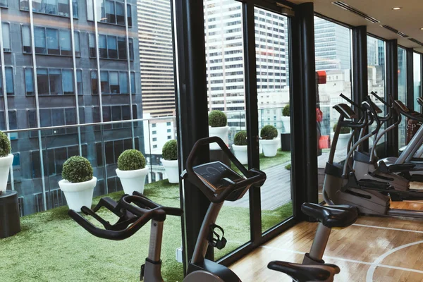 Vista de perto do equipamento de exercício no ginásio e vasos de flores na varanda — Fotografia de Stock