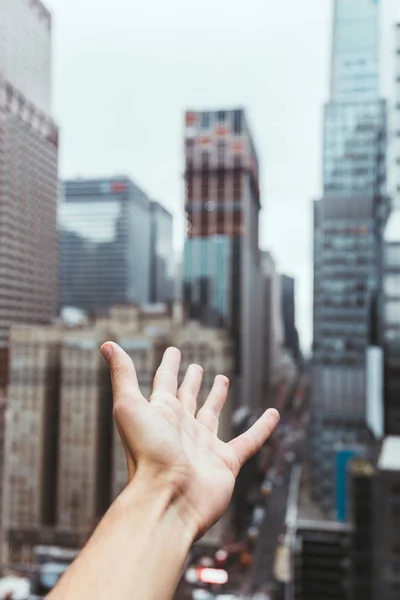 Vue partielle de la main masculine et vue floue de la ville de New York en arrière-plan — Photo de stock