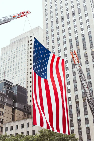 Vista de cerca de la bandera americana y edificios en la ciudad de Nueva York, EE.UU. - foto de stock