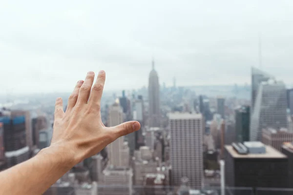 Vista parcial de la mano masculina y borrosa ciudad de Nueva York en el fondo - foto de stock