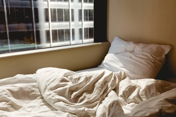 Закрыть вид на пустую кровать возле окна в гостиничном номере — стоковое фото