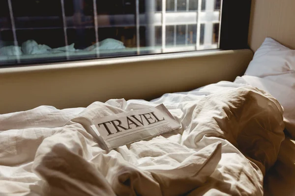 Close up view of travel newspaper on bed in hotel room — Stock Photo