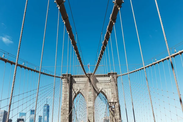 Brooklyn bridge with american flag on clear blue sky and manhattan on background, new york, usa — Stock Photo