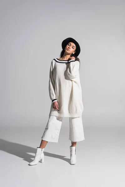 Attractive african american girl in stylish white clothes and hat looking at camera on white — Stock Photo