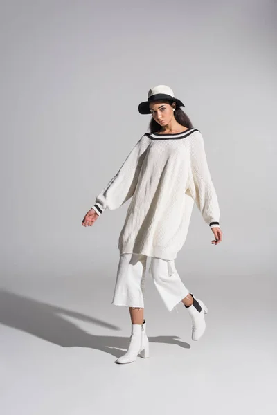 Attrayant afro-américain fille dans élégant blanc vêtements et chapeau marche et regardant caméra sur blanc — Photo de stock