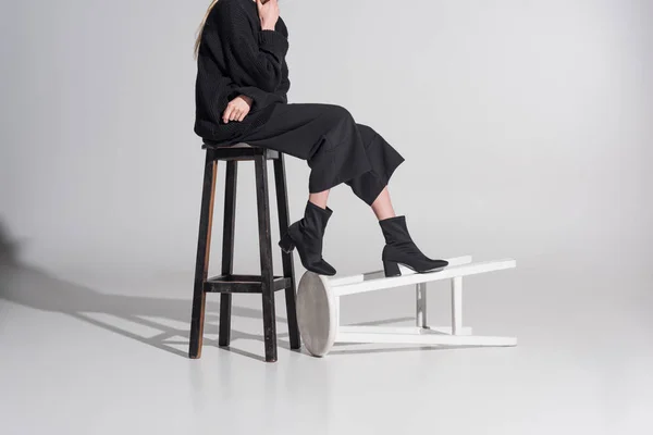 Cropped image of woman in black clothes sitting on chair on white — Stock Photo