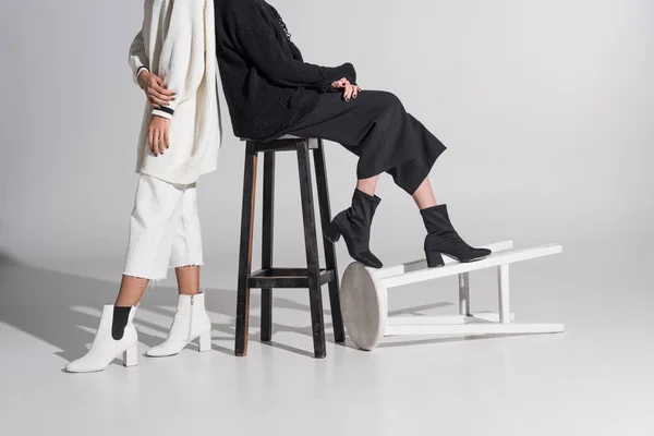 Imagem cortada de mulheres multiculturais em roupas pretas e brancas com cadeiras em branco — Fotografia de Stock