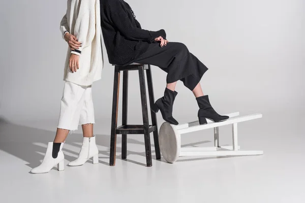 Cropped image of multicultural women in black and white clothes with chairs on white — Stock Photo