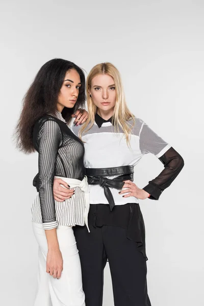 Attractive multicultural lesbian couple in black and white clothes hugging and looking at camera isolated on white — Stock Photo