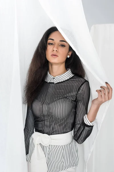 Beautiful african american girl in stylish clothes looking out form tulle on white — Stock Photo