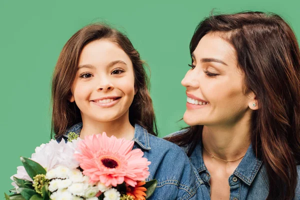 Retrato de mãe sorridente e filha com flores isoladas em verde — Fotografia de Stock