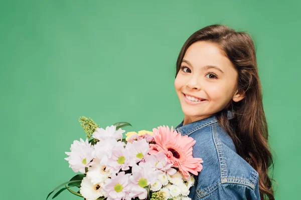 Lächelndes Kind mit Blumenstrauß, das isoliert auf Grün in die Kamera blickt — Stockfoto