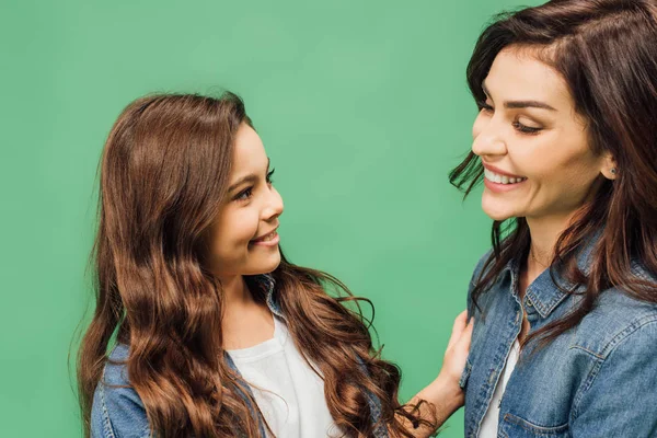 Portrait of happy mother and daughter smiling and looking at each other isolated on green — Stock Photo