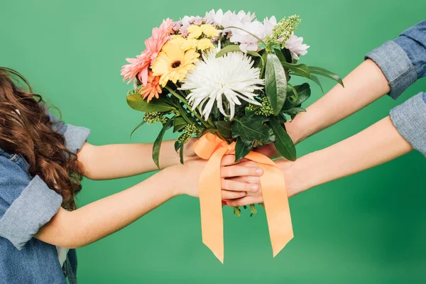 Cropped view of mother and daughter holding flowers isolated on green — Stock Photo