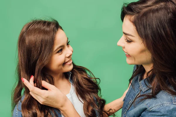 Portrait of mother and daughter smiling and looking at each other isolated on green — Stock Photo