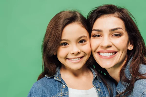 Beautiful mother and adorable daughter looking at camera isolated on green — Stock Photo