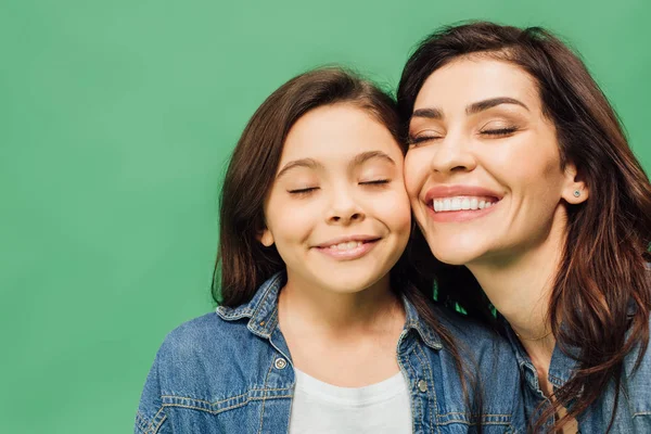 Retrato de hermosa madre e hija con los ojos cerrados aislados en verde - foto de stock