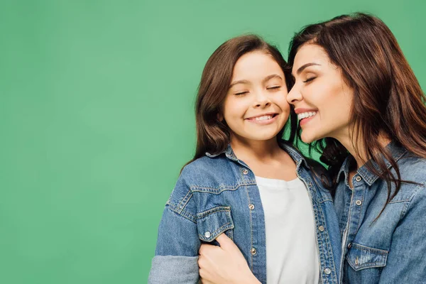Glückliche Mutter und Tochter mit geschlossenen Augen, die sich isoliert auf Grün umarmen — Stockfoto