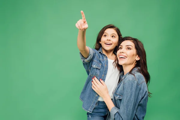 Animado filha apontando com o dedo enquanto feliz mãe olhando para cima isolado no verde — Fotografia de Stock