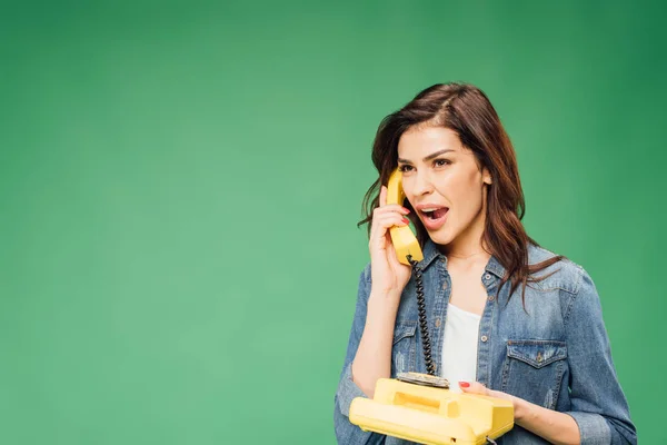 Beautiful surprised woman talking on vintage telephone isolated on green — Stock Photo