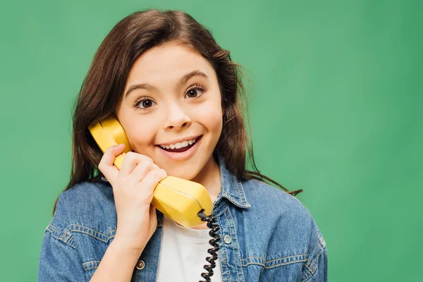 Aufgeregtes Kind, das am alten Telefon spricht und isoliert auf grün in die Kamera blickt — Stockfoto