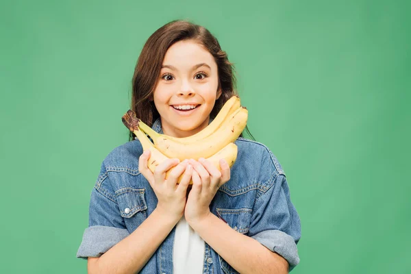 Excité enfant tenant des bananes et regardant caméra isolé sur vert — Photo de stock