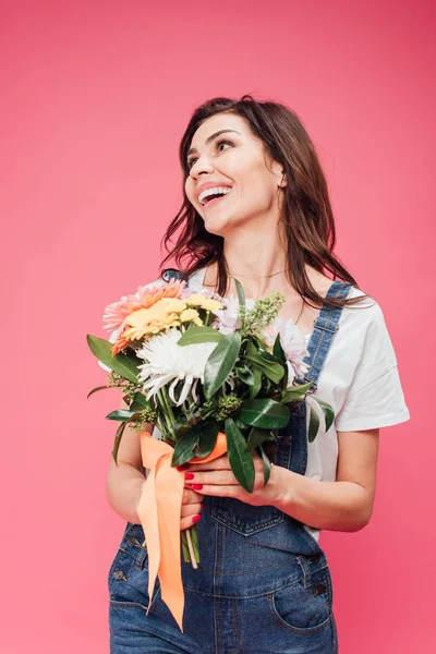 Mujer alegre sosteniendo ramo de flores aislado en rosa - foto de stock