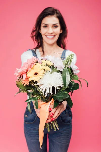 Sonriente mujer sosteniendo ramo de flores aislado en rosa - foto de stock