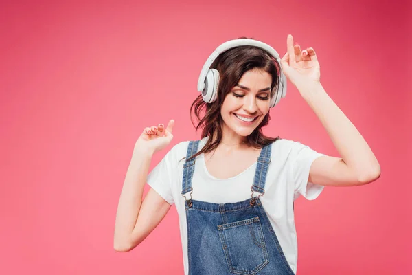 Mujer escuchando música en auriculares aislados en rosa - foto de stock