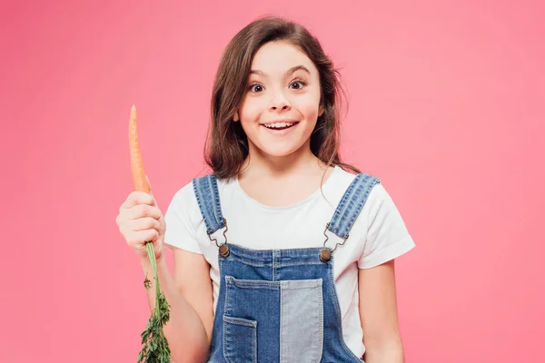 Happy kid holding carrot isolated on pink — Stock Photo