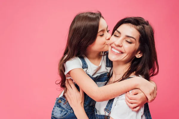 Filha beijando mãe feliz isolado em rosa — Fotografia de Stock