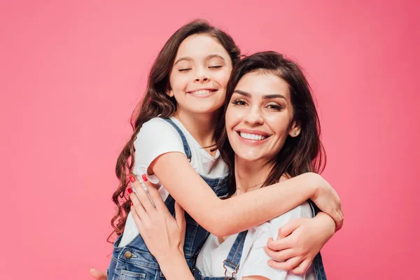 Hija abrazando feliz madre aislado en rosa - foto de stock