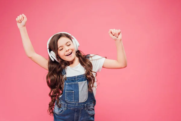 Child with closed eyes and headphones dancing isolated on pink — Stock Photo