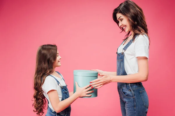 Figlia che dà il regalo a madre durante giorno di madri isolato su rosa — Foto stock