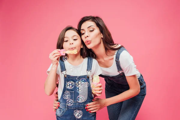 Mom and daughter blowing soap bubbles isolated on pink — Stock Photo