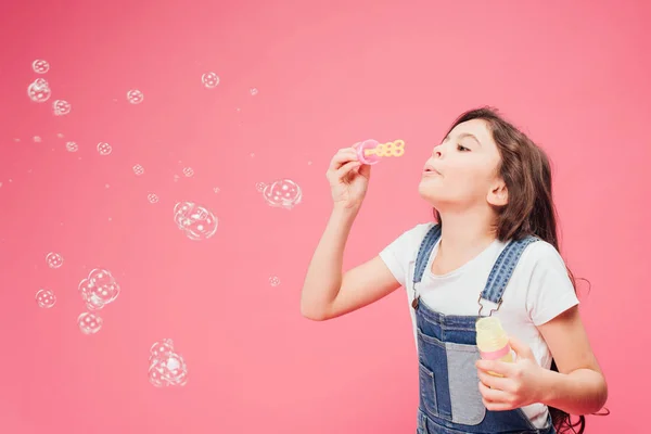 Fröhliches Kind bläst Seifenblasen isoliert auf rosa — Stockfoto