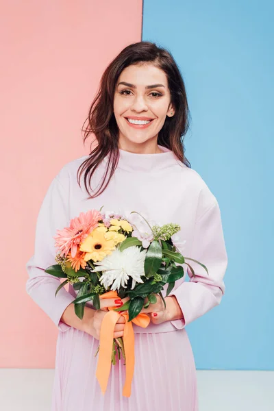 Sonriente mujer sosteniendo flores en las manos en feliz día de las madres - foto de stock