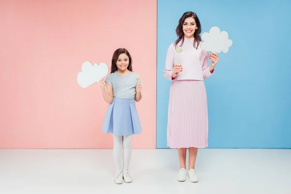 Adorabile bambino e attraente donna che tiene bolle vocali e guardando la fotocamera su sfondo blu e rosa — Foto stock