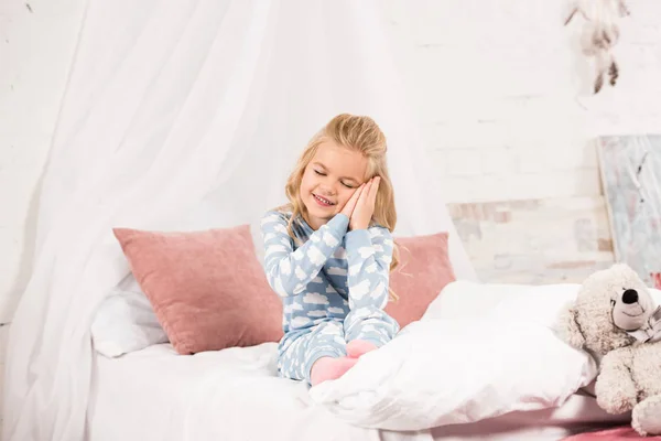 Adorable sleepy child sitting on bed with closed eyes — Stock Photo